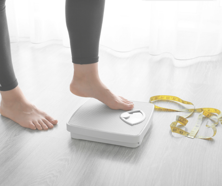 Woman on scale with measuring tape.