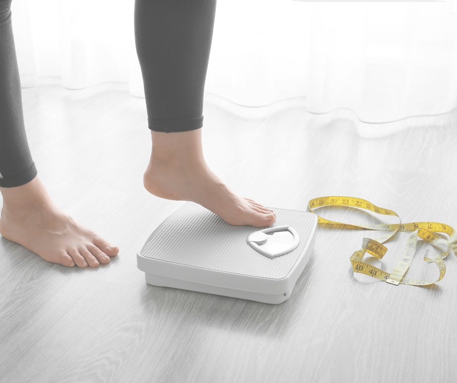 Woman on scale with measuring tape.